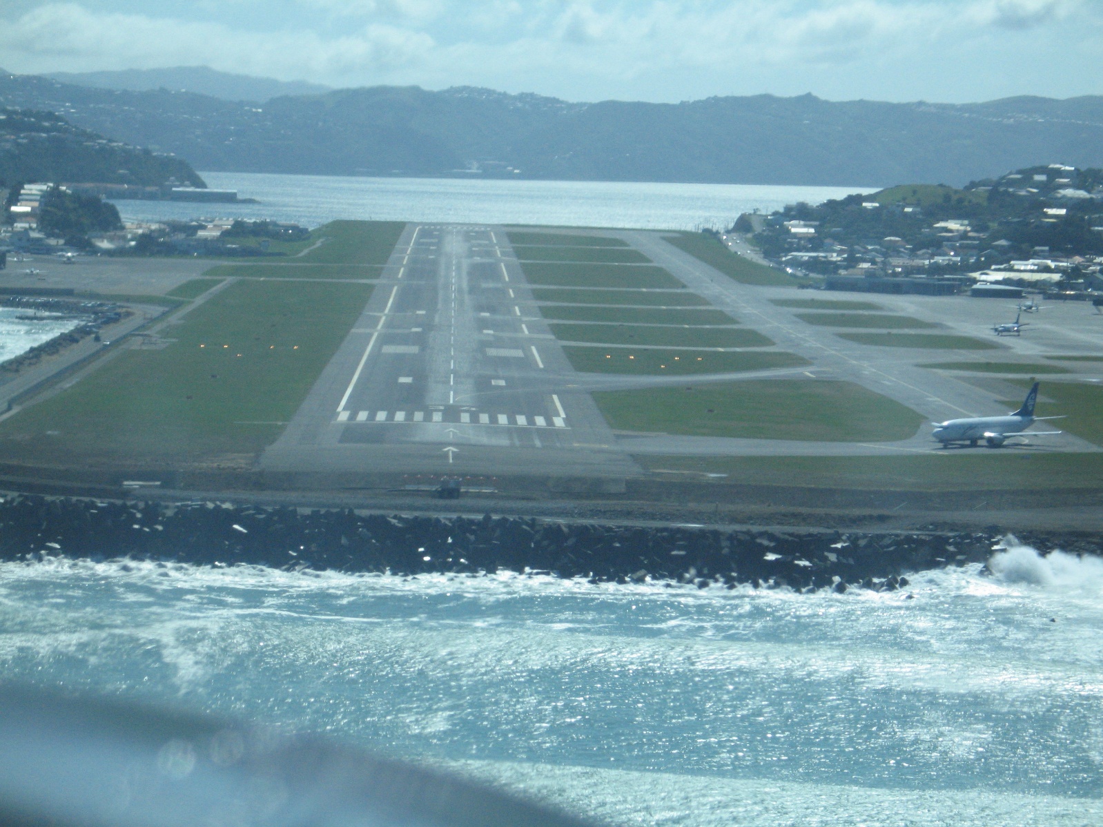 View of a coastal airport runway with an airliner taxiing