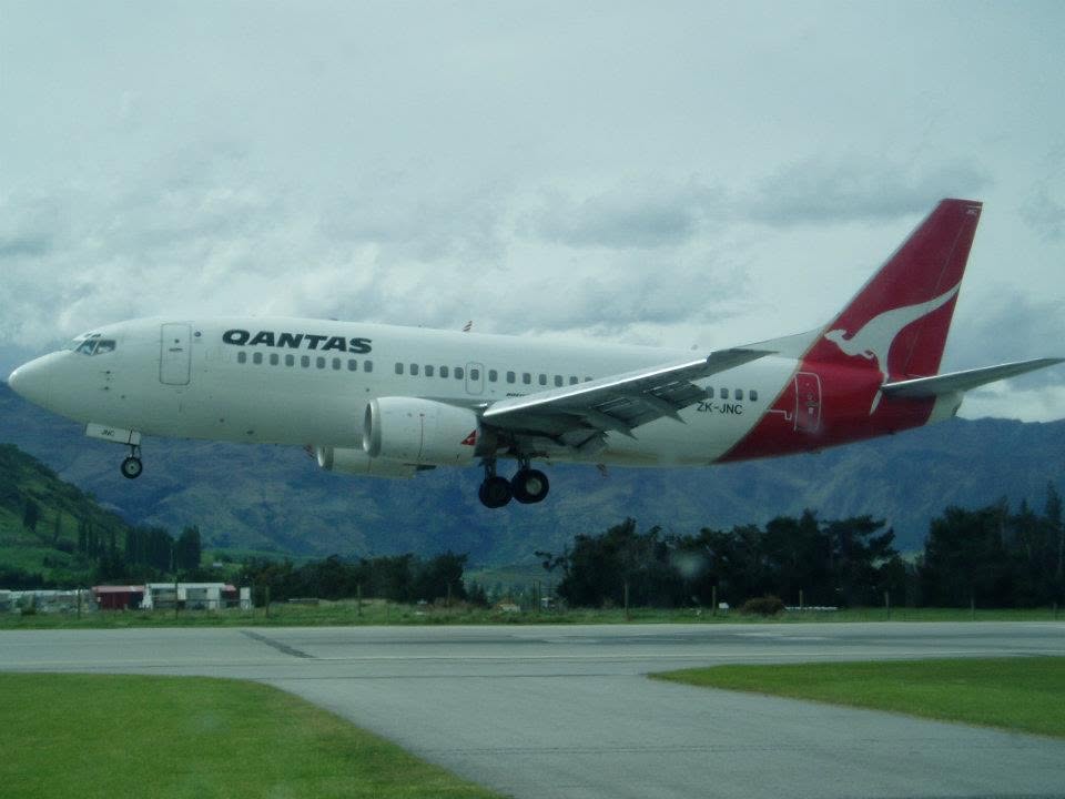 Qantas Boeing 737 on approach with hills in the background